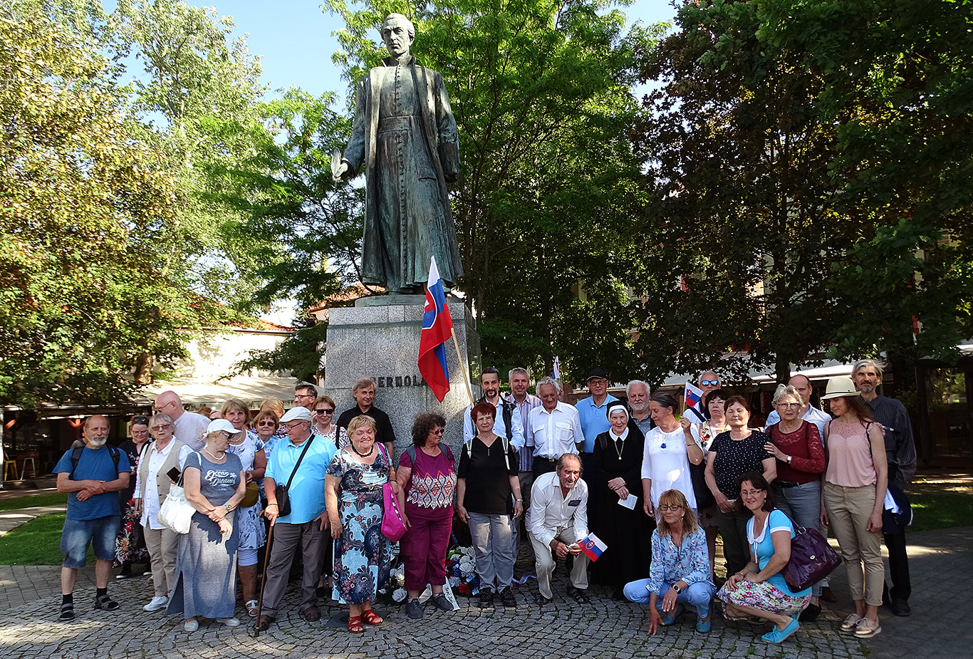 Účastníci národného podujatia so slovenskou vlajkou pri pamätníku